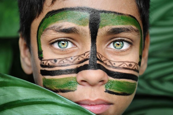 Los ojos verde de este niño escondido detrás de ramas
